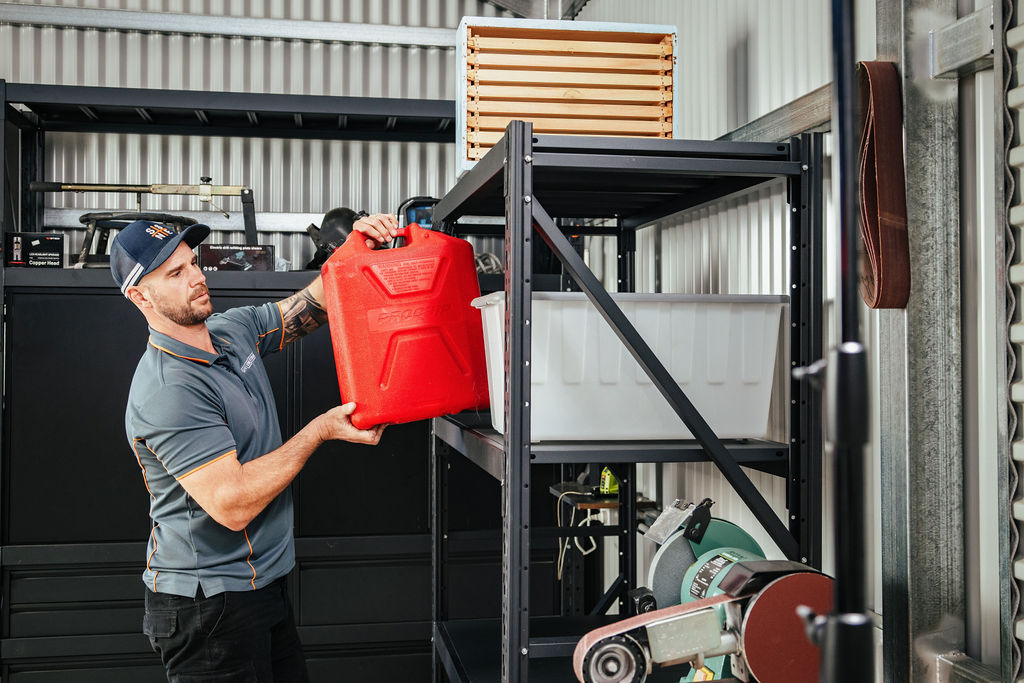 Organising a garage shelve, Ben Edney placing a petrol canister in shelf 