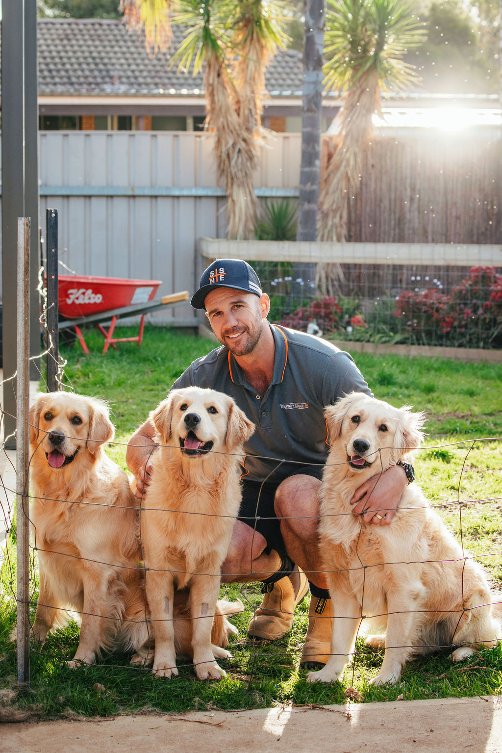 Ben with three Golden retrievers in yard of shelving and storage ne