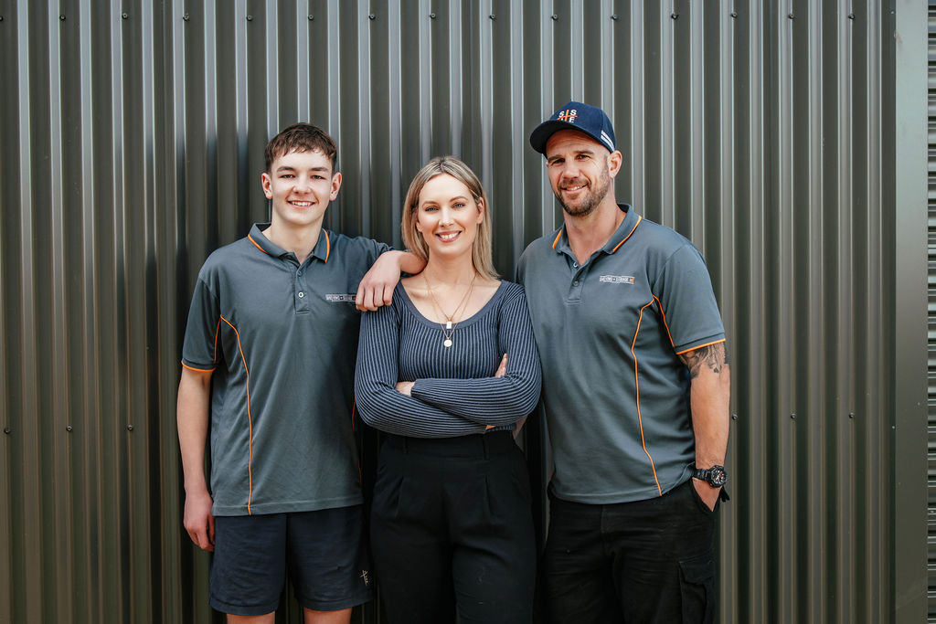 Ben Edney, Simone Edney and Dylan group portrait standing in from of shed.